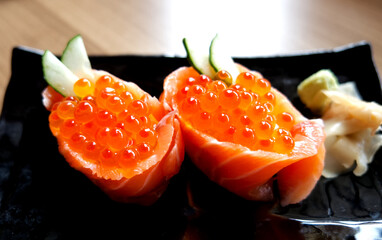 Delicious Japanese salmon roe gunkan maki sushi garnished with cucumber and wasabi. © oatautta