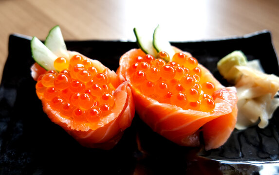 Delicious Japanese salmon roe gunkan maki sushi garnished with cucumber and wasabi.