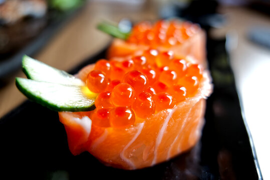 Delicious Japanese salmon roe gunkan maki sushi garnished with cucumber and wasabi.