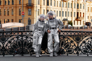 Couple of astronauts on an old bridge with a cast iron railing look at each other, romantic date concept © Ulia Koltyrina