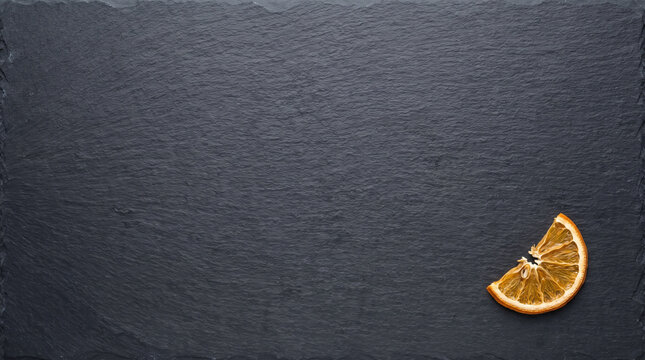 A Single Dried Orange Slice Placed Elegantly on a Dark Slate Background, Highlighting Natural Textures and Colors in Culinary Presentation