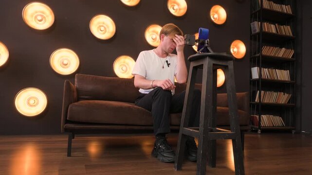Young Man Vlogging or Streaming Live Content with a Smartphone in a Modern Studio Interior