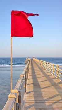 A red warning flag on a wooden pier, selective focus.