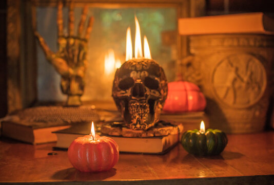 Maya carved skull candle with burning flames on old spell book, pagan ritual altar and esoteric concept 