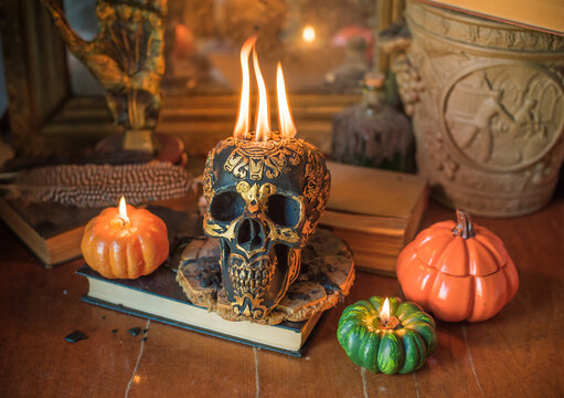 Maya carved skull candle with burning flames on old spell book, pagan ritual altar and esoteric concept 