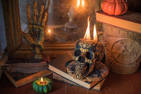 Maya carved skull candle with burning flames on old spell book, pagan ritual altar and esoteric concept 