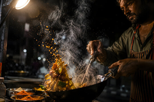 Chef tossing food in wok pan with flying sparks and smoke on night street food stall representing authentic asian culinary art