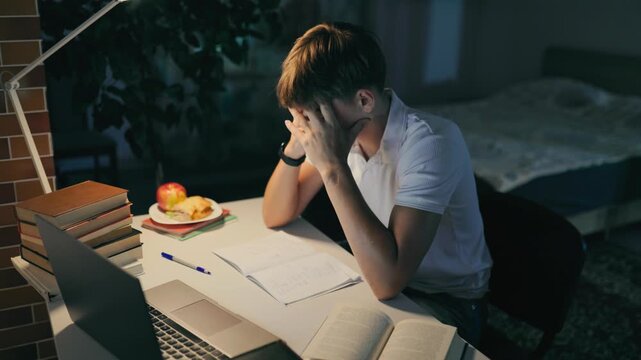 Frustrated teenage boy throwing his pen failing a difficult night homework.