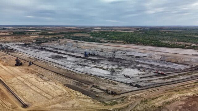 Visonta, Hungary open-cast lignite mine near M&aacute;tra Power Plant with excavators, conveyor belts and terraced pit roads in an industrial landscape, filmed by drone.