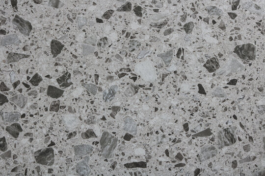 A full-frame background of a light grey terrazzo surface embedded with dark grey, white, and black stone fragments.