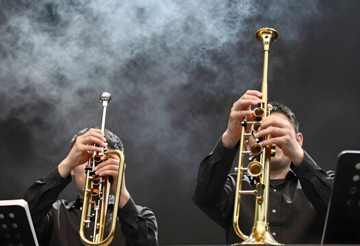 Jazz performance and musical collaboration, two trumpet players performing on stage with smoke effects and dramatic lighting in a concert hall