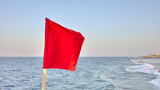 A red warning flag by the sea, selective focus.