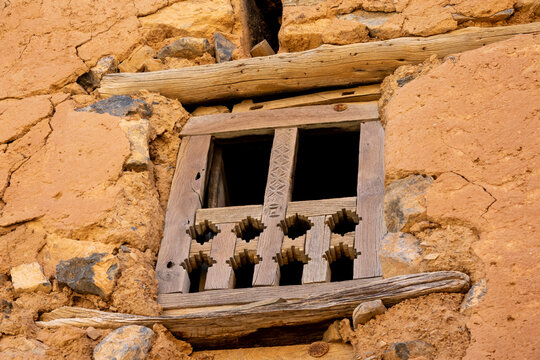 Close-up of a carved wooden window lattice screen set into a crumbling mudbrick wall, Ad Dakhiliyah Region, Al Hamra, Oman