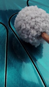 Vertical video close up view of soft grey mallet hitting a metallic turquoise steel tongue drum or tank drum