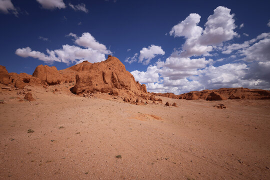 Paesaggio desertico con formazioni rocciose erose e cielo azzurro con nuvole bianche