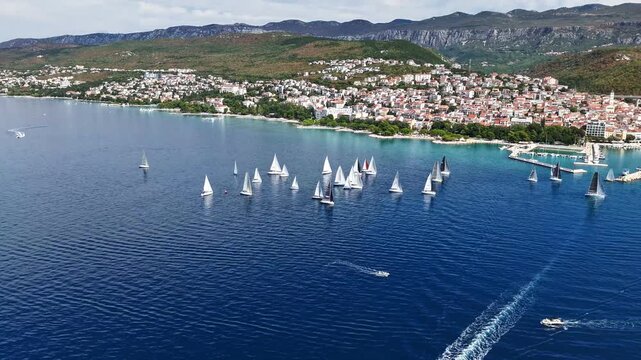 Aerial hyperlapse over the Adriatic Sea showing a coastal Croatian town, a sailing regatta with numerous sailboats