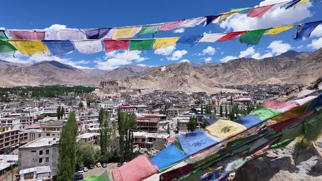 Leh, India : Panoramic footage of Leh Palace on the hilltop overlooking the city in Ladakh, India with residential and mosque under blue sky. Taken through colorful prayer's flags