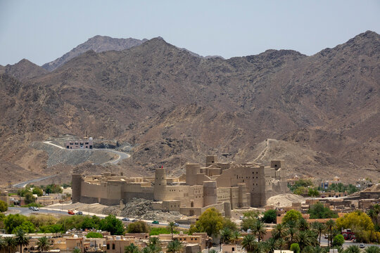 Panoramic view of Bahla Fort's mudbrick walls and towers backed by rugged mountains, Ad Dakhiliyah Governorate, Bahla, Oman