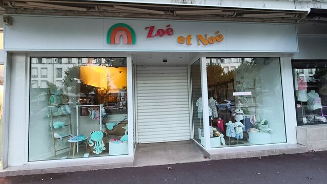 Royan, France - July 15, 2026: Charente-Maritime. Nouvelle-Aquitaine. Storefront of children's clothing shop "Zoe et Noe" featuring colorful displays and a rainbow logo in urban setting