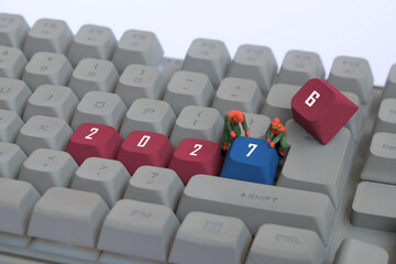 Obraz premium Miniature workers changing 2026 to 2027 on computer keyboard with red and blue keycaps
