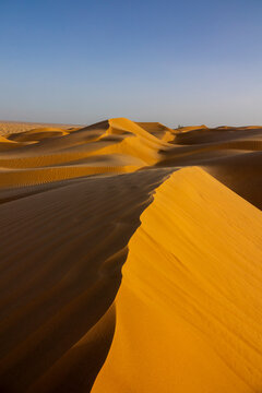 Vertical view of a large sand dune ridge with rippled patterns leading toward the horizon, Dhofar Governorate, Rub al Khali, Oman
