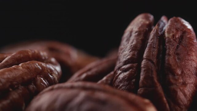 Extreme macro shot of fresh premium pecan nuts with selective focus, rotating slowly on dark background with artistic lighting. Perfect for healthy eating, gourmet food, culinary, and dietary content.