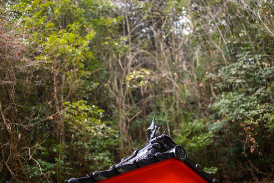 Macro landscape view of an ornate traditional Japanese temple roof detail set against a dense forest background in Japan