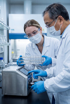Two researchers loading a vial rack into a laboratory analyzer