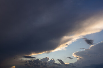 Unusual Cloud Formation with a Bright Blue Opening Through Dark Clouds. Dramatic natural sky featuring a massive dark cloud formation interrupted by a striking bright blue opening. The strong visual  © Nadiia