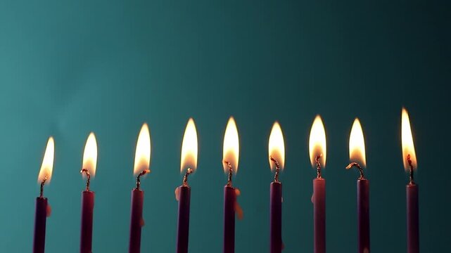 Nine metallic pink and purple birthday candles burning in a row against a dark blue background, isolated. Happy Birthday card design concept.  Bottom lower border edge a lot of copy space. 
