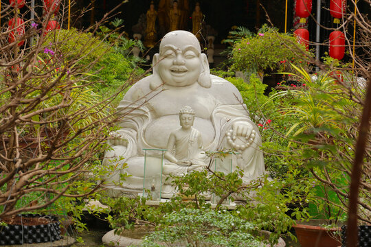 White marble Budai Laughing Buddha and small Shakyamuni statue in zen garden sanctuary, traditional feng shui wealth symbol