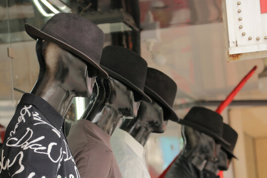 Menswear retail store fashion boutique display, rhythm row of black male mannequins wearing fedora hats and polo shirts
