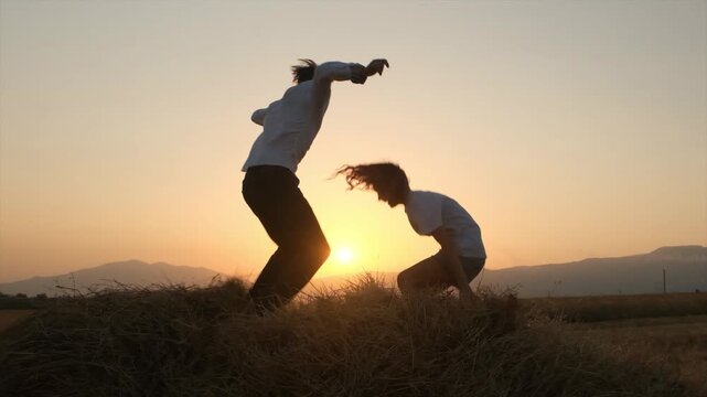 Two happy children, a boy and a girl, joyfully jump on a soft haystack in a rural field at sunset, expressing genuine childlike happiness in slow motion Childhood memories, happy moments, carefree joy
