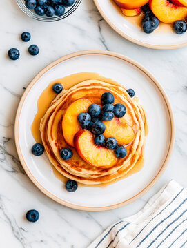 Golden Fluffy Pancakes with Maple Syrup Blueberries and Peaches on Marble