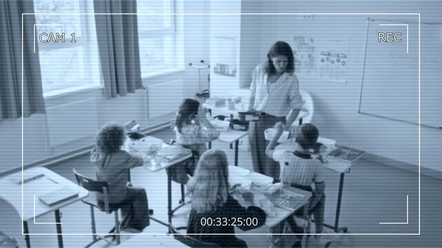 Caucasian female teacher holding recycling bins while children sort trash in classroom during ecology lesson recorded on CCTV camera. Ideal for school surveillance and educational safety campaigns