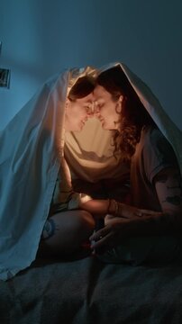 Vertical video of young Caucasian couple sitting under blanket and touching foreheads. Clip suited for dating app promo, Valentine advertising and romantic lifestyle branding