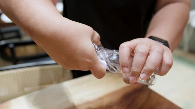 Close Up of Hands Crushing and Twisting Plastic Bottle for Recycling