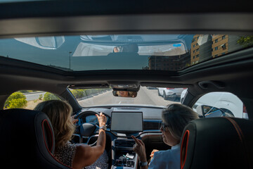 Obraz premium Women driving modern car with sunroof on city trip