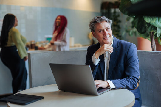 Mature businessman using laptop smiling at camera