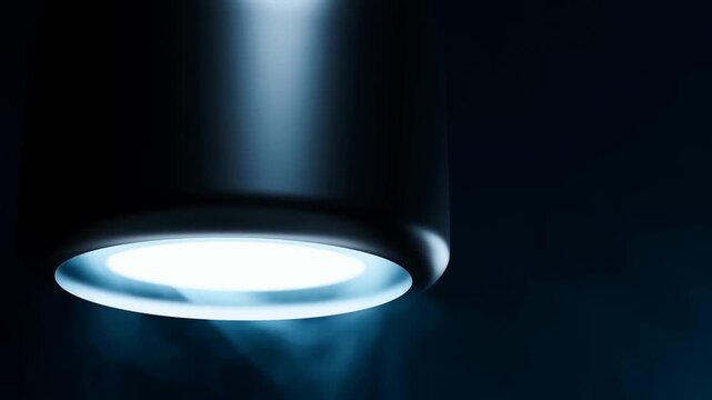 Black cylindrical pendant light with glowing underside in a dark blue interior