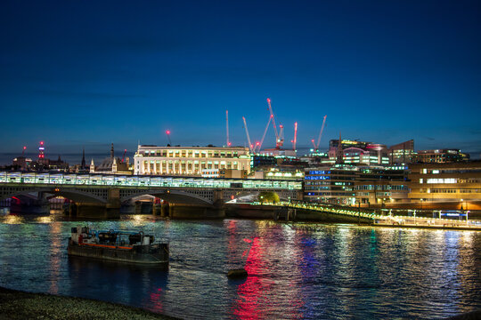 Nighttime London Riverside with Illuminated Bridge and Historic Building