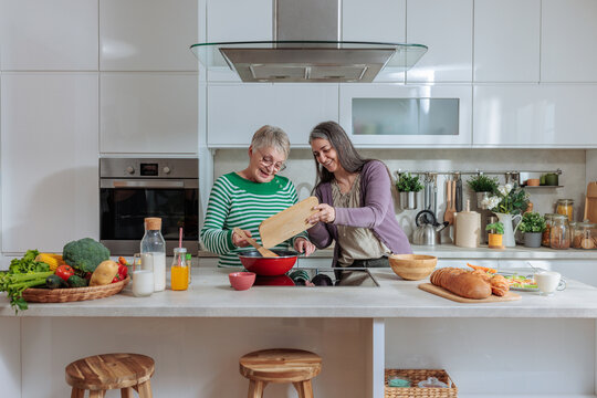 Mother and daughter cooking healthy food together in kitchen
