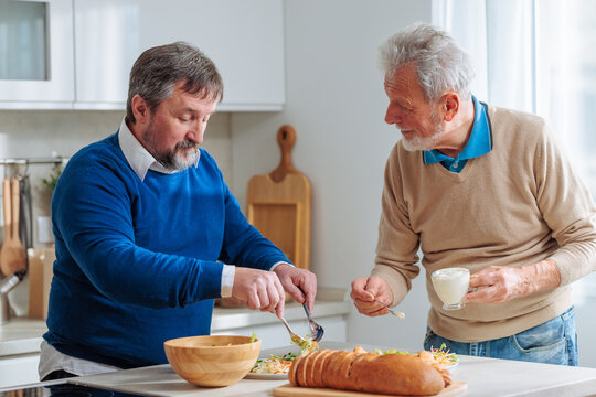 Senior men preparing fresh meal in kitchen