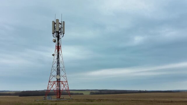 5G Telecommunication Cell Tower Aerial View in Rural Field Under Cloudy Sky