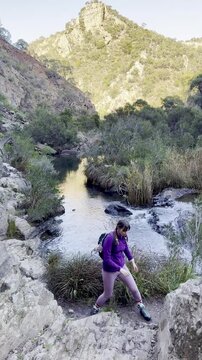 A girl hiker rock scrambles along a cliffside above the river, on a tough section of the Werribee Gorge Circuit Walk, near Melbourne, Victoria, Australia.
