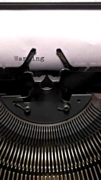 Vertical Macro Shot of Vintage Typewriter Typing the Word Warning