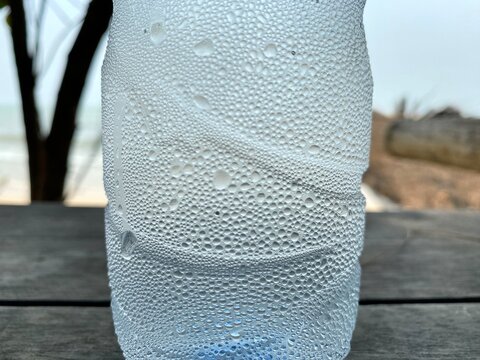 Close-up of a cold bottle covered with water droplets and condensation, creating a refreshing visual associated with hydration, freshness, and cool beverages