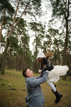 Father throws up child in sky. Loving father lifts his happy little daughter up high and they play together outdoors in a pine forest.
