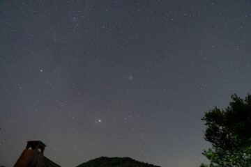 Pleiades cluster Taurus constellation and bright Jupiter over dark hill. © badescu
