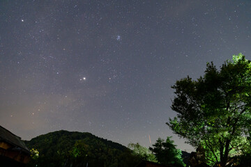 Pleiades cluster Taurus constellation and bright Jupiter over dark hill. © badescu